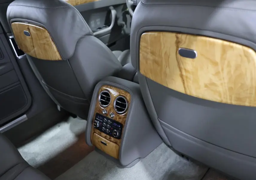 Vue intérieure arrière de la Bentley Continental Flying Spur 2006, cuir gris et boiseries claires élégantes.