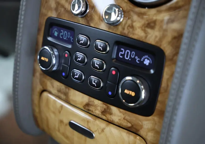 Détail de la console centrale en bois clair avec commandes de climatisation digitale de la Bentley Continental Flying Spur.