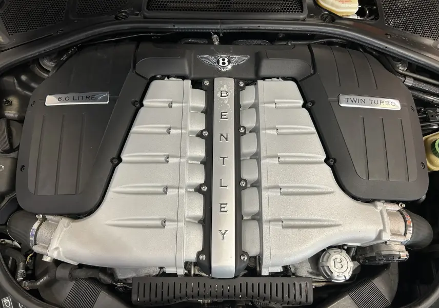Vue plongeante sur le moteur 6.0 L Twin Turbo de la Bentley Continental Flying Spur, avec logo Bentley central.