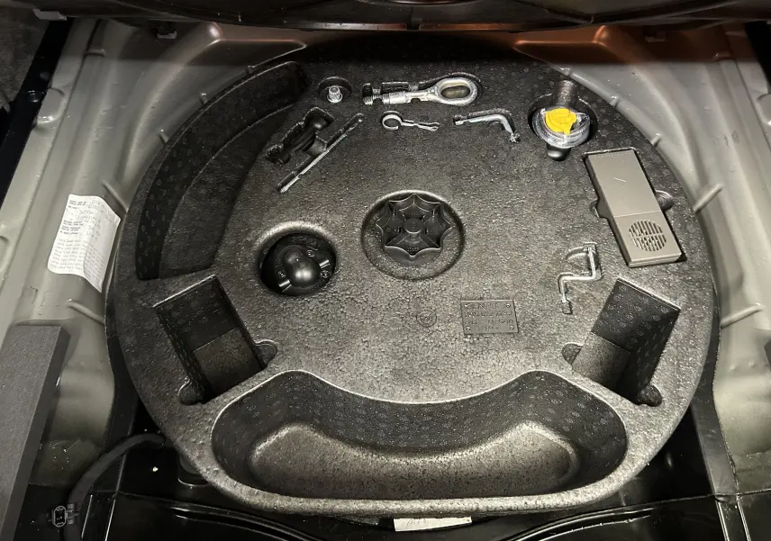 Coffre ouvert montrant le rangement d'outils et accessoires d'origine Bentley sur fond gris clair.