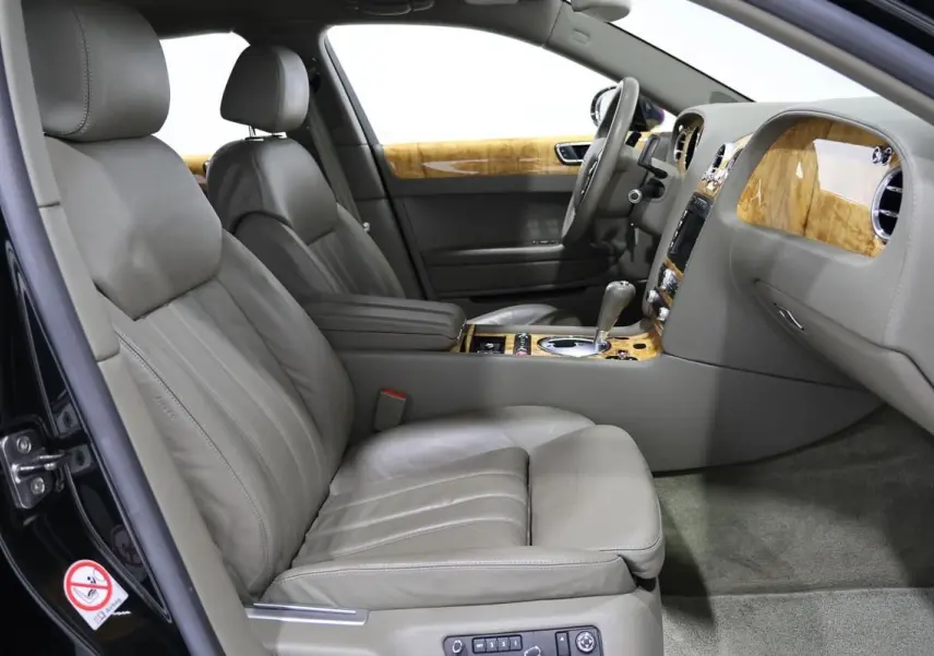 Vue intérieure côté conducteur de la Bentley Continental Flying Spur 2006, sièges cuir gris et boiseries claires élégantes.