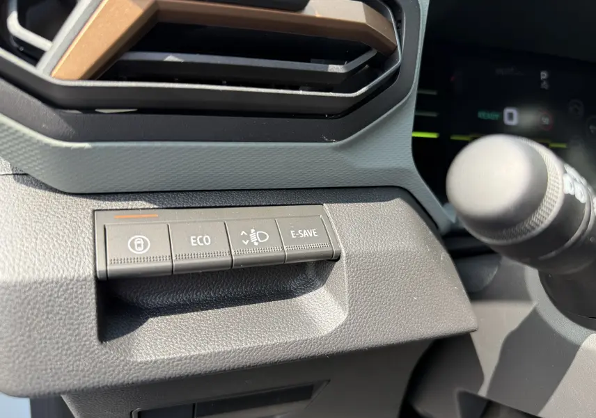 Gros plan sur les boutons de commande à gauche du volant dans le tableau de bord du Dacia Duster Hybrid 155 Extreme.