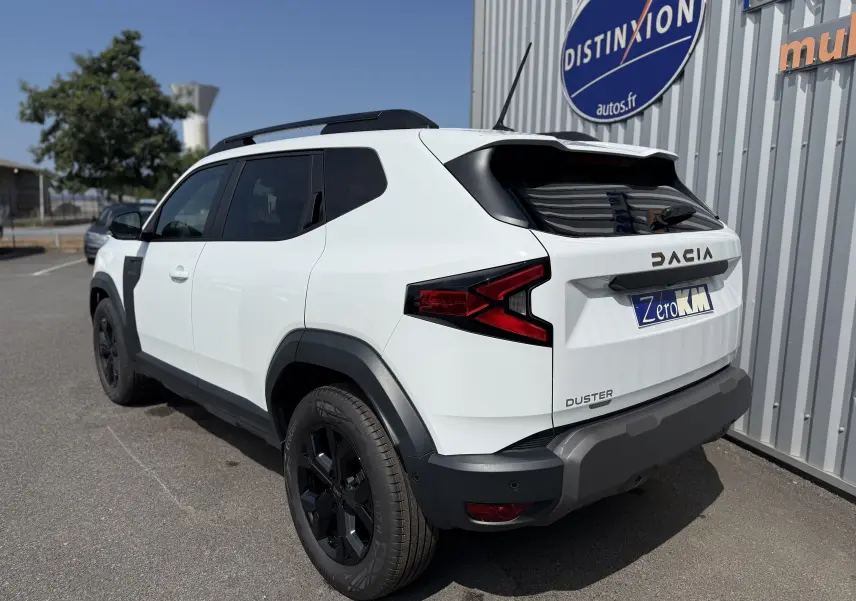 Vue 3/4 arrière droite du Dacia Duster Hybrid 155 Extreme blanc glacier avec jantes noires et détails noirs contrastants.