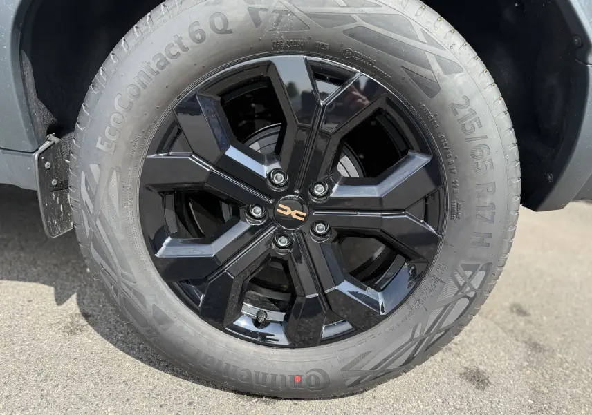 Gros plan sur la jante noire brillante 17 pouces du Dacia Duster Hybrid 155 Extreme blanc glacier, avec pneu Continental Ecocontact 6Q.