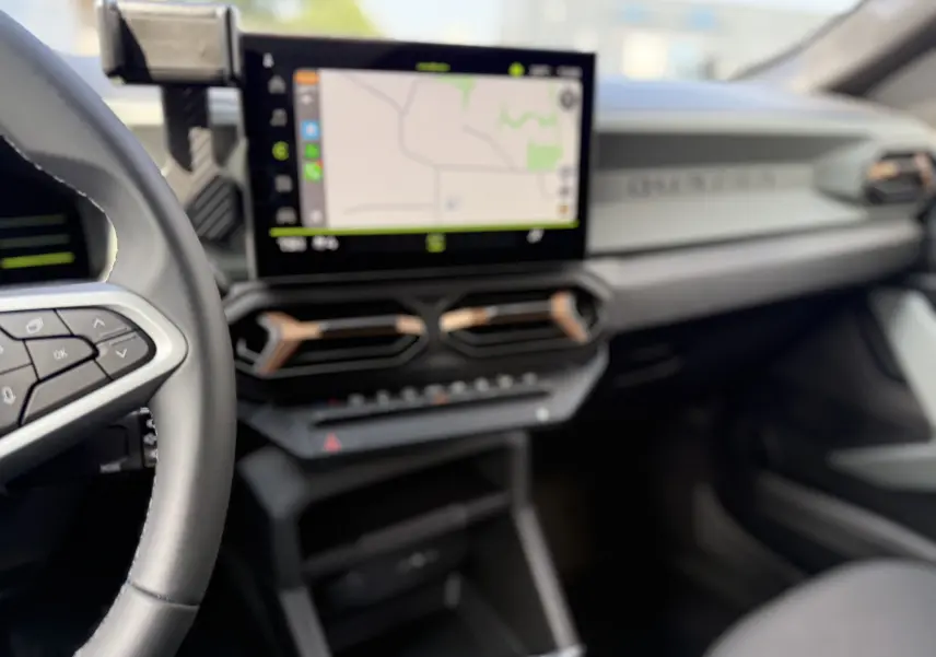 Vue intérieure du tableau de bord du Dacia Duster Hybrid 155 Extreme 2026, avec écran tactile central et volant partiel visible.