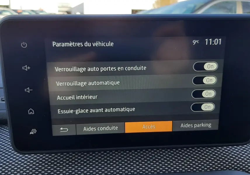 Écran tactile intérieur du Dacia Jogger affichant les paramètres de verrouillage et essuie-glace, avec vue partielle extérieure.