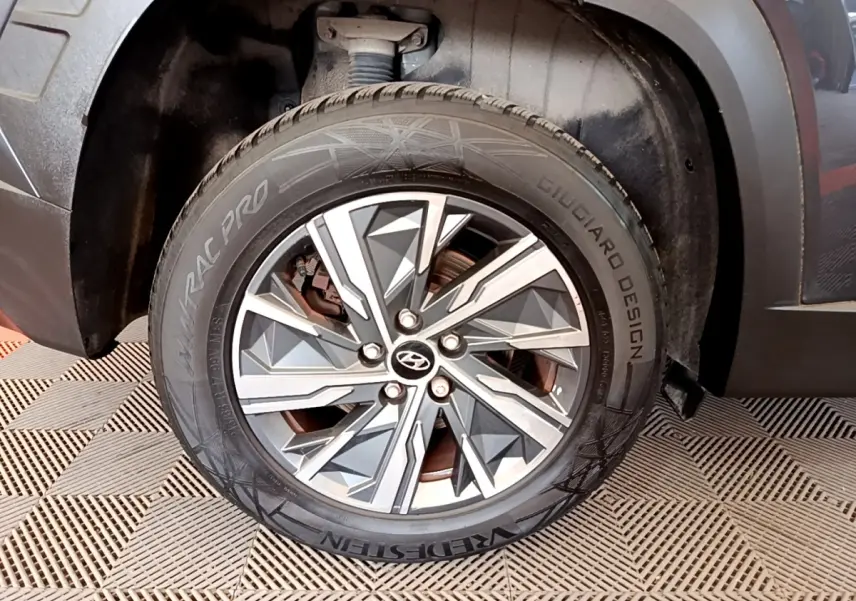 Gros plan sur la roue avant droite gris foncé du Hyundai Tucson 1.6 Hybrid 230 Creative avec jante alu au design géométrique.