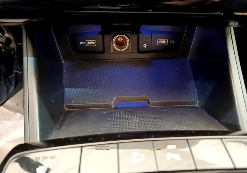 Gros plan sur la console centrale du Hyundai Tucson gris foncé, montrant ports USB et prise 12V avec éclairage bleu.