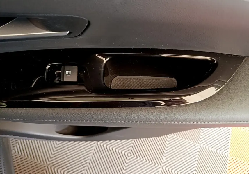 Poignée intérieure de porte côté gauche du Hyundai Tucson gris foncé, avec bouton de verrouillage des vitres.