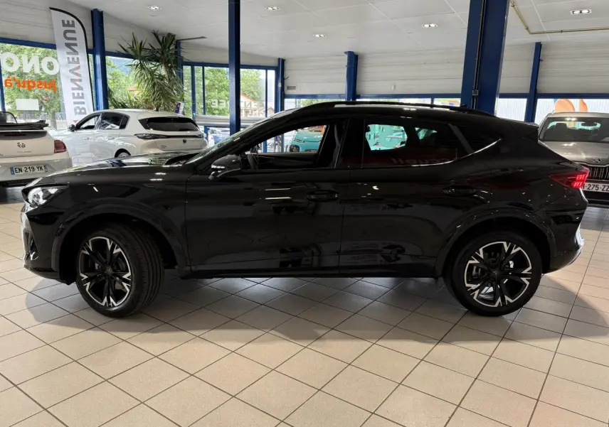 Vue de profil côté gauche d'une CUPRA Formentor 2025 noire Night avec jantes alliage 18'' en showroom.