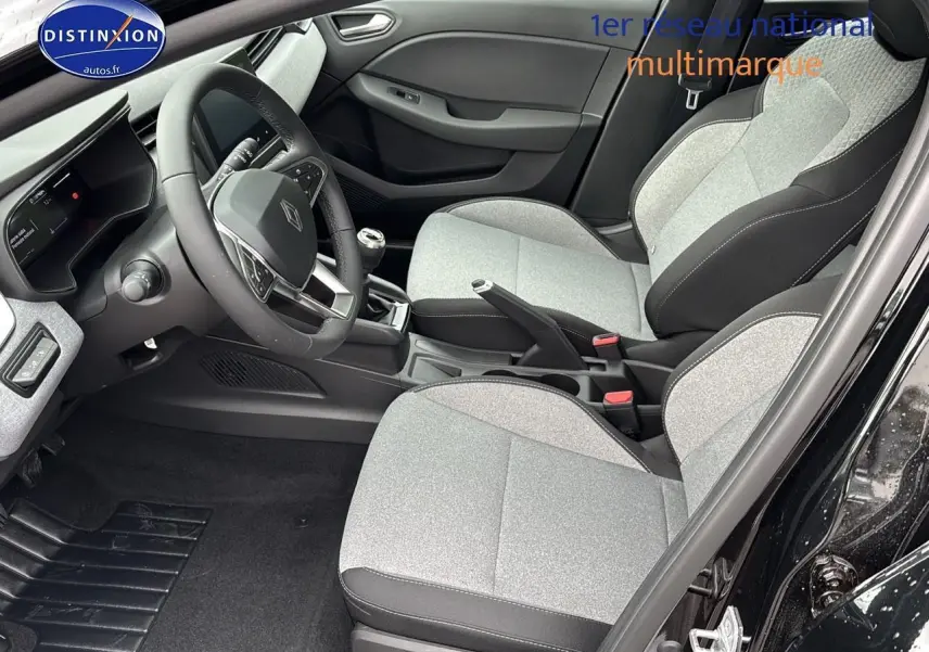 Intérieur avant droit d'une Renault Clio V 2025 noir étoilé, sièges gris clair et volant cuir avec boîte manuelle.