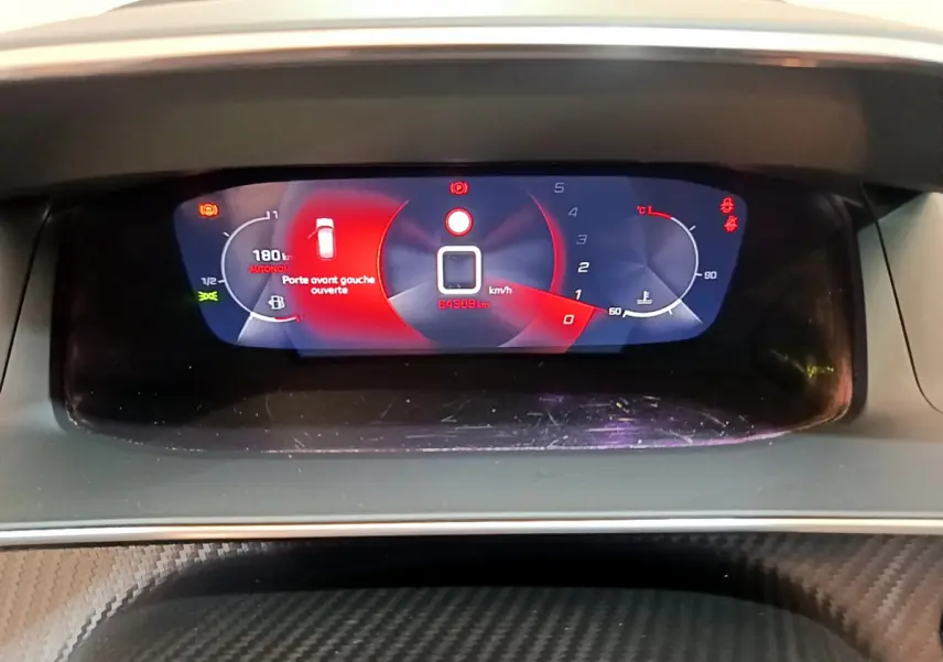 Tableau de bord numérique de Peugeot 208 blanc, affichage multifonctions avec alerte porte avant gauche ouverte.