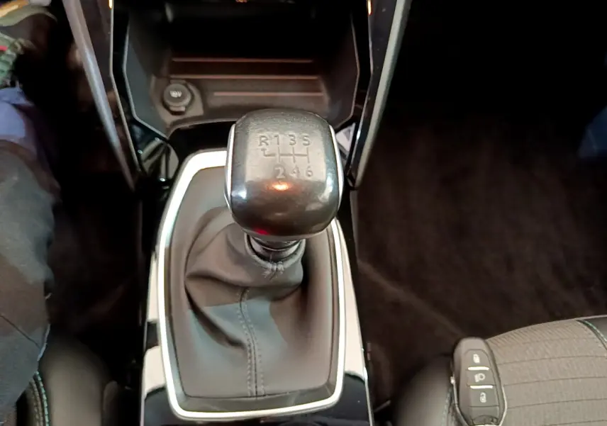 Le levier de vitesses manuel noir vu de dessus dans l'habitacle d'une Peugeot 208 blanche de 2020.