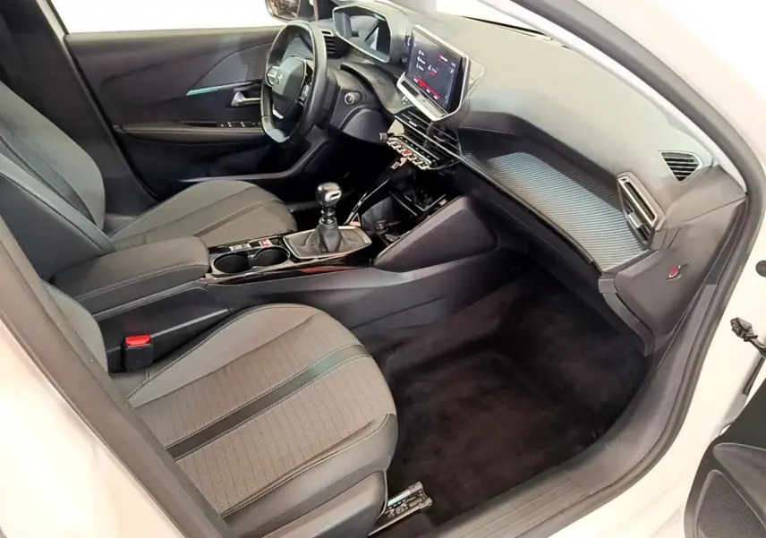 Intérieur de la Peugeot 208 blanche, vue côté conducteur, tableau de bord moderne avec écran tactile et volant cuir.