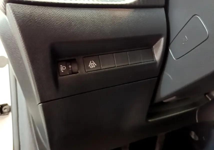 Gros plan sur les commandes noires côté gauche du tableau de bord d'une Peugeot 208 blanche, version Allure Business.