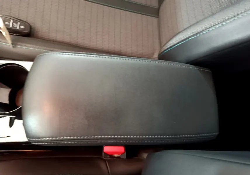 Accoudoir central noir avec surpiqûres bleues dans l'habitacle d'une Peugeot 208 blanche PureTech 100 S&S Allure Business 2020