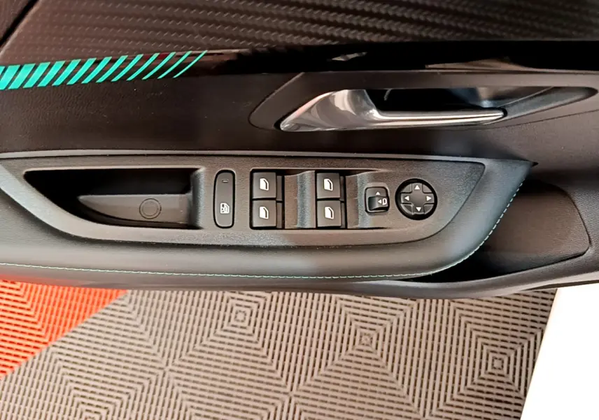 Gros plan sur la commande des vitres côté conducteur de la Peugeot 208 blanche, avec poignée de porte chromée.