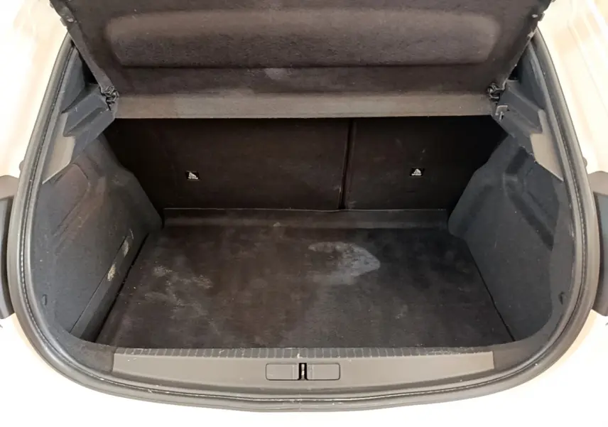 Coffre ouvert noir vu de face sur Peugeot 208 blanc, montrant l'espace de chargement vide et propre.
