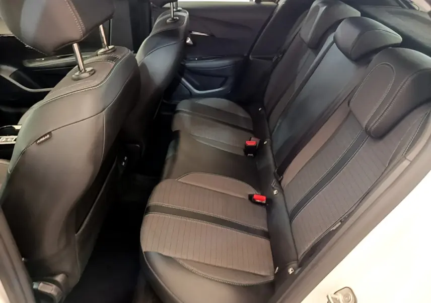 Vue côté droit de la banquette arrière noire et grise du Peugeot 208 blanc, avec appuie-têtes et ceintures visibles.