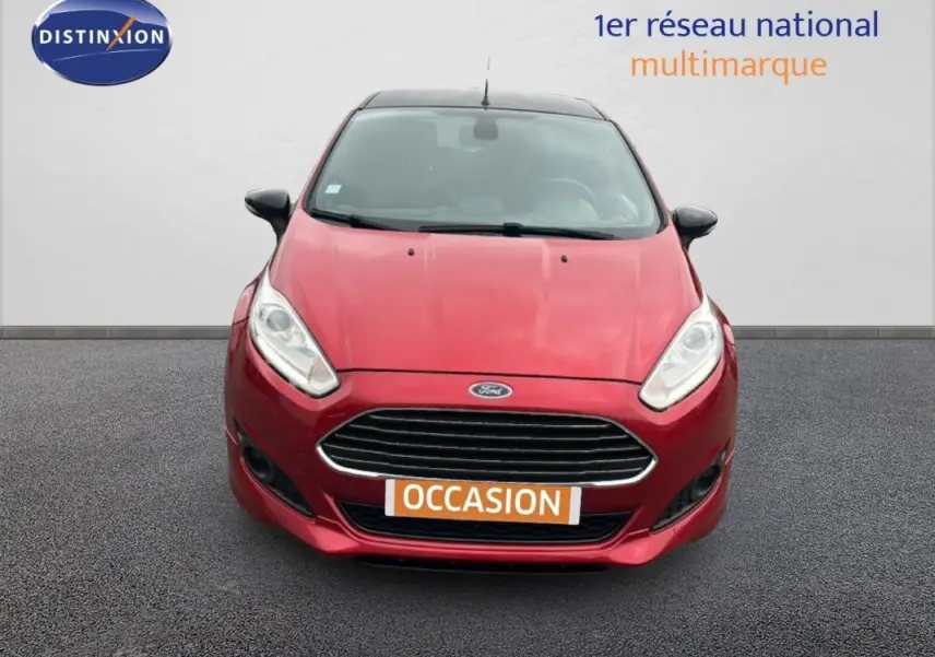 Vue avant d'une Ford Fiesta rouge 2017 avec calandre chromée et phares allumés, affichant une plaque "OCCASION".
