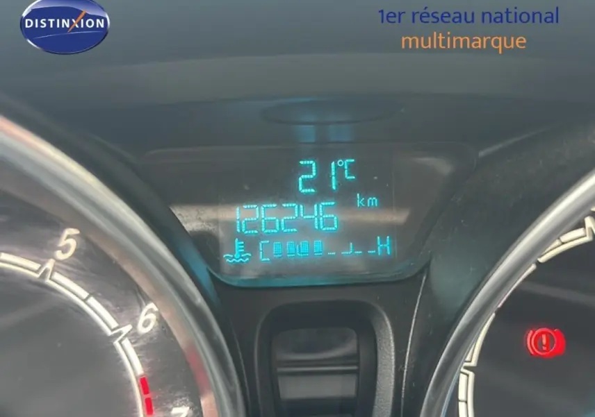 Gros plan sur le tableau de bord numérique bleu de la Ford Fiesta rouge, affichant 126246 km et 21°C.