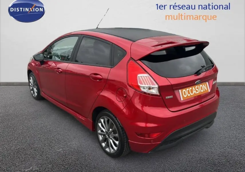 Ford Fiesta rouge vue 3/4 arrière droit, avec toit noir, vitres surteintées et jantes alliage 16 pouces.