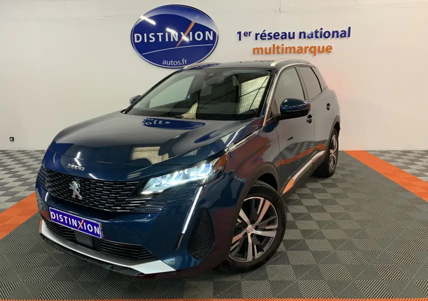 Vue 3/4 avant d'un Peugeot 3008 PureTech 130 Allure Pack bleu Célèbes avec phares allumés en showroom.