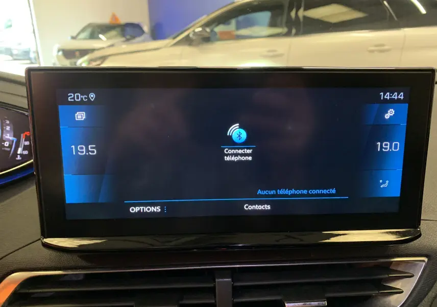 Gros plan sur la console centrale du Peugeot 3008 bleu, montrant les commandes tactiles et boutons métalliques rétroéclairés.