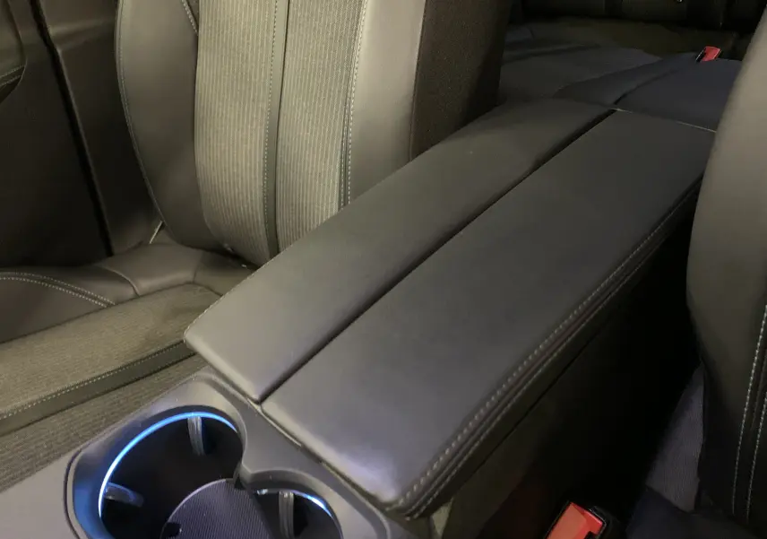 Gros plan sur l'accoudoir central noir et les sièges avant en tissu et cuir du Peugeot 3008 PureTech 130 Allure Pack.