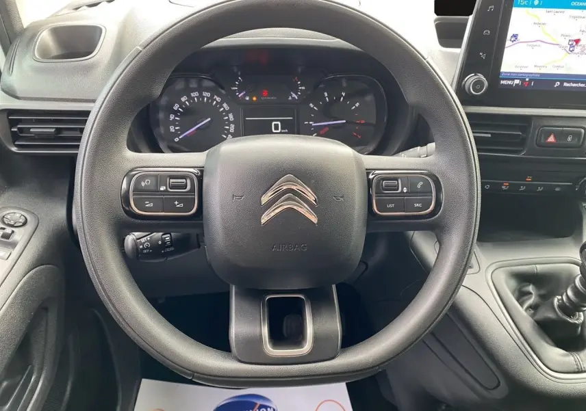 Vue centrée sur le volant noir du Citroën Berlingo 2019, avec tableau de bord et écran GPS visible à droite.