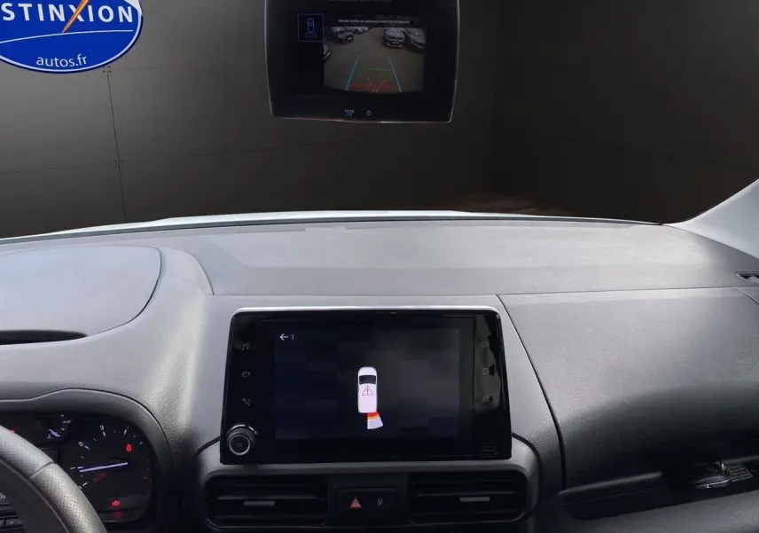 Vue intérieure du tableau de bord du Citroën Berlingo blanc, avec écran tactile affichant l'aide au stationnement et caméra de recul.