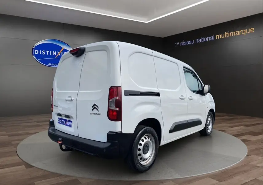 Vue 3/4 arrière droite d'un utilitaire Citroën Berlingo blanc avec hayon et pare-chocs noirs dans un showroom.