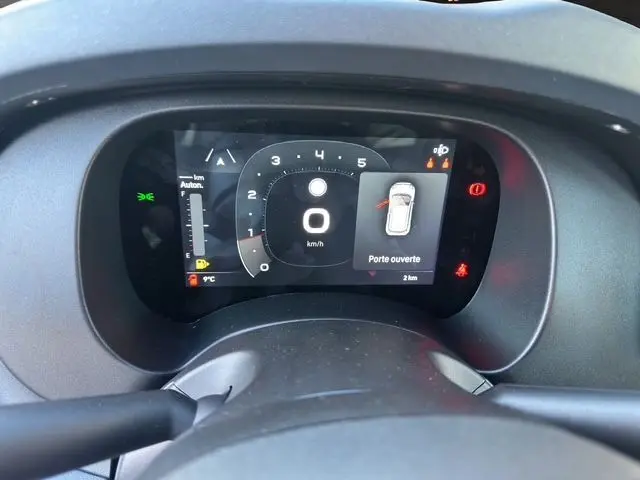 Tableau de bord numérique de la Fiat Panda 2025 montrant la vitesse à 0 km/h et une porte ouverte, vue depuis le siège conducteur.