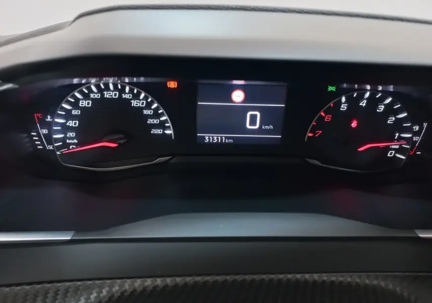 Vue rapprochée du tableau de bord numérique de la Peugeot 208 blanche, affichant 0 km/h et 31 311 km au compteur.
