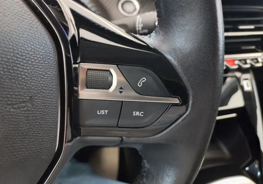 Gros plan sur les commandes du volant cuir noir de la Peugeot 208 PureTech 100 S&S Allure 2021.