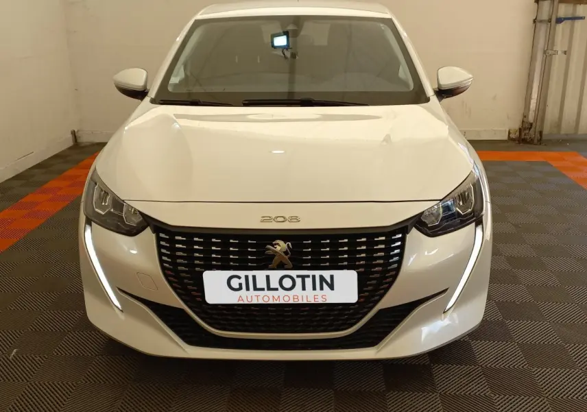 Vue frontale d'une Peugeot 208 PureTech 100 S&S Allure blanche avec calandre noire et feux LED en forme de griffes.