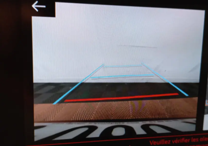 Vue arrière caméra de recul de la Peugeot 208 blanche PureTech 100 S&S Allure avec lignes de guidage colorées.