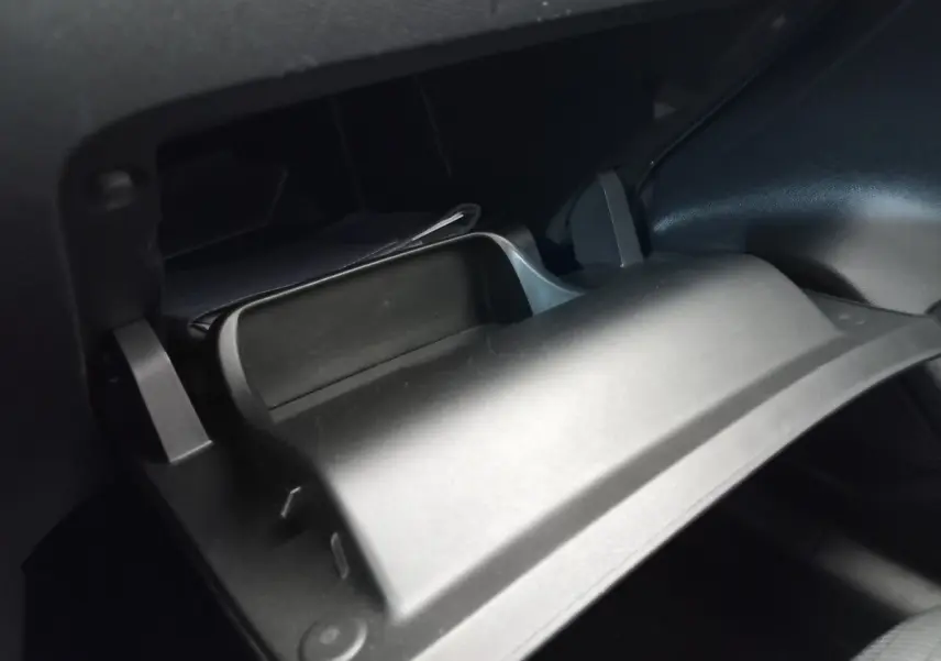 Gros plan sur la boîte à gants ouverte du Peugeot 208 PureTech 100 S&S Allure blanc, intérieur noir.