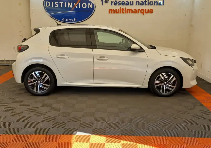 Profil côté gauche d'une Peugeot 208 PureTech 100 S&S Allure blanche, avec jantes alliage et vitres teintées.