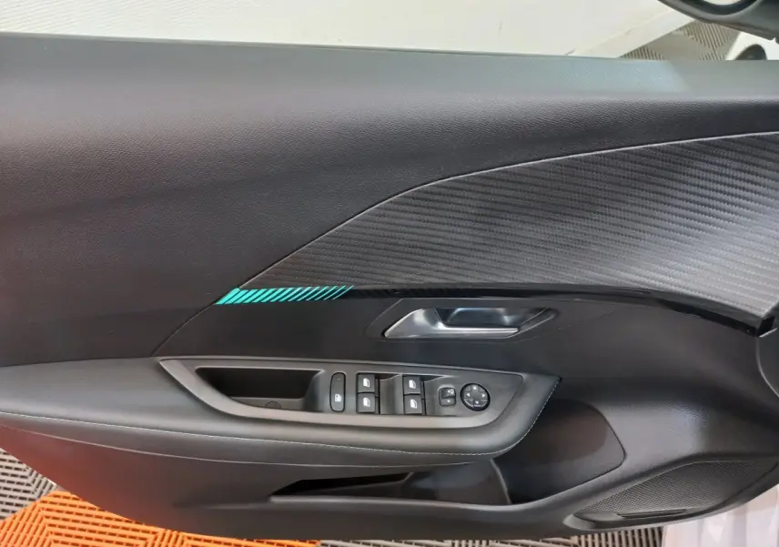 Vue rapprochée de la porte avant gauche noire avec insert carbone et commandes des vitres du Peugeot 208 blanc.