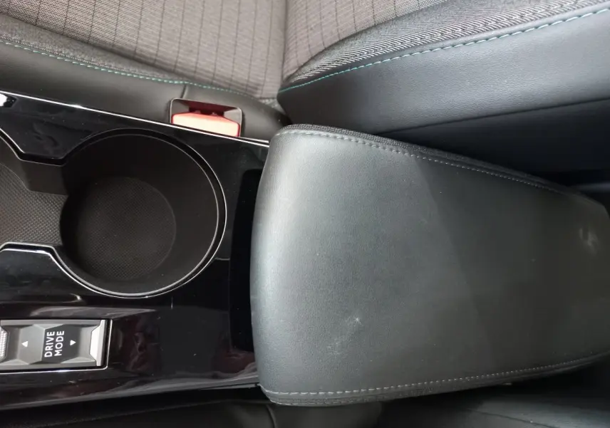 Gros plan sur la console centrale noire et l'accoudoir en cuir noir de la Peugeot 208 PureTech 100 S&S Allure 2021.