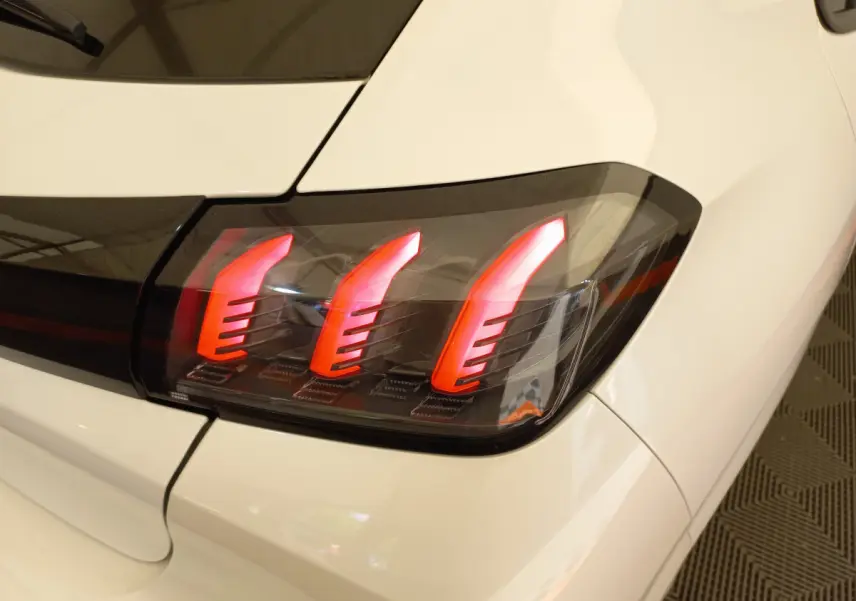 Gros plan sur le feu arrière droit rouge du Peugeot 208 blanc PureTech 100 S&S Allure 2021, soulignant son design moderne.