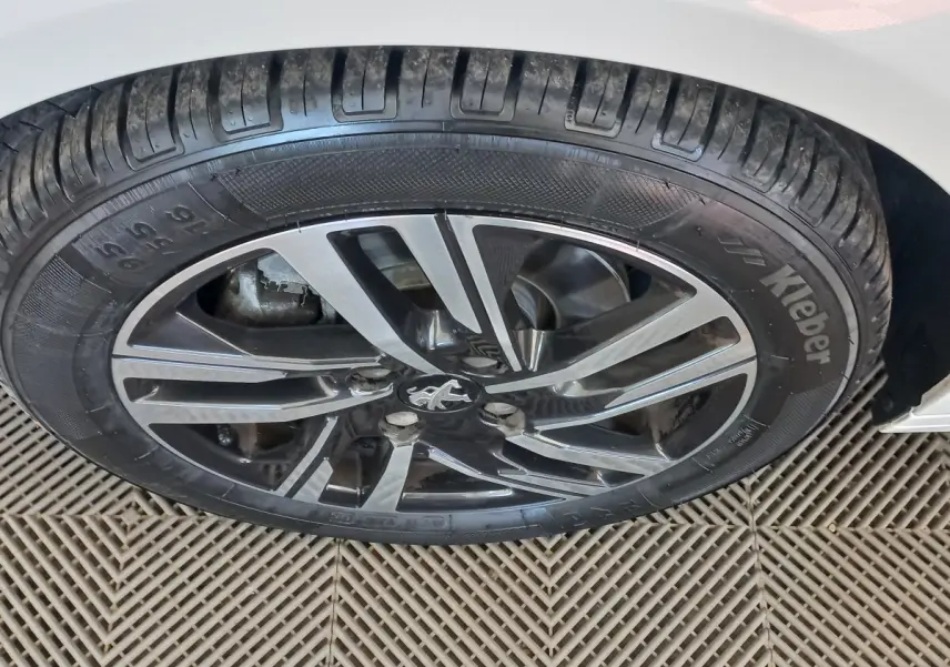 Gros plan sur la jante alliage noire et argentée d'une Peugeot 208 blanche, vue côté gauche arrière.