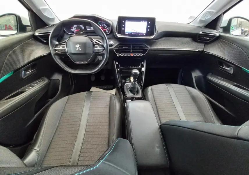 Intérieur noir de la Peugeot 208 PureTech 100 S&S Allure 2021, vue avant centrée sur le tableau de bord et volant cuir.