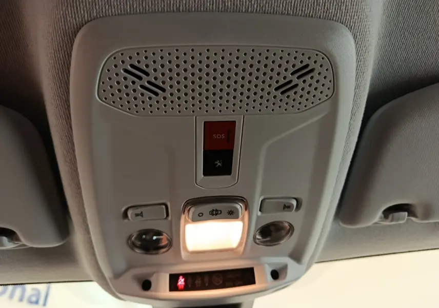 Vue intérieure du plafonnier blanc de la Peugeot 208 électrique 2021 avec éclairage et bouton SOS rouge allumé.