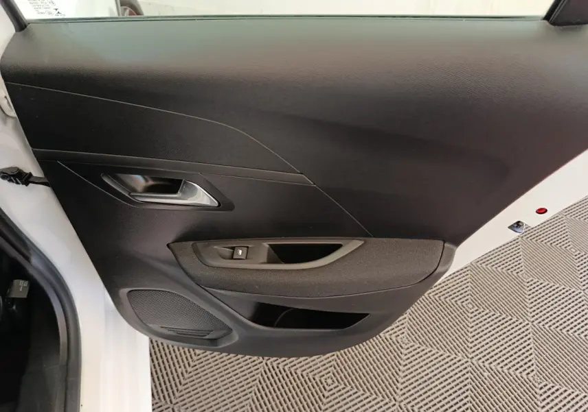 Vue rapprochée de la porte arrière gauche noire avec poignée argentée d'une Peugeot 208 électrique blanche.