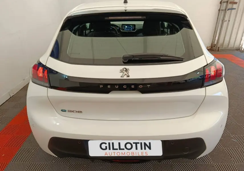 Vue arrière d'une Peugeot 208 électrique blanche avec bande noire et feux arrière LED distinctifs.