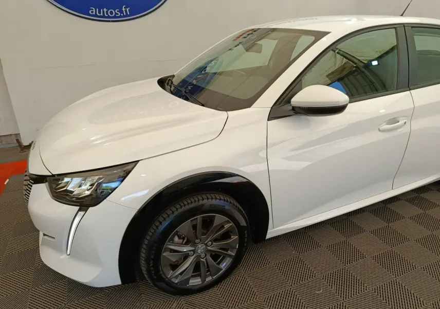 Peugeot 208 électrique blanche vue 3/4 avant droit, avec phares LED et jantes alliage foncé.