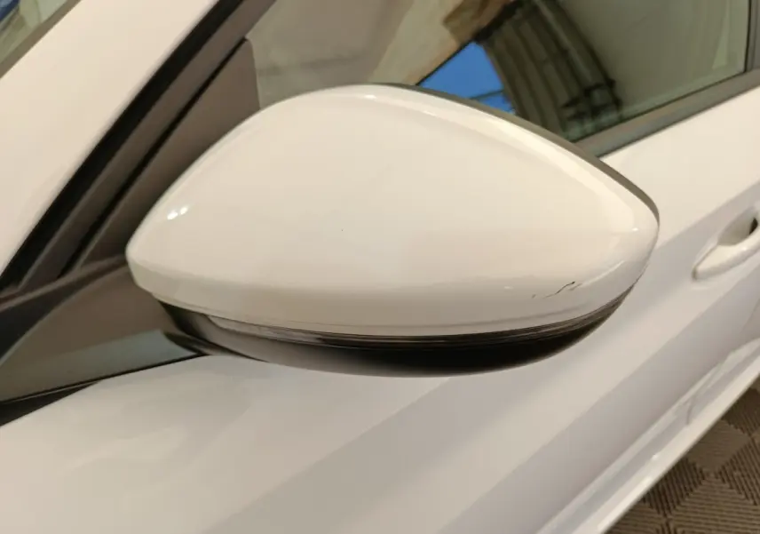 Rétroviseur côté gauche blanc de Peugeot 208 électrique 2021, vue rapprochée avec portière et poignée visibles.