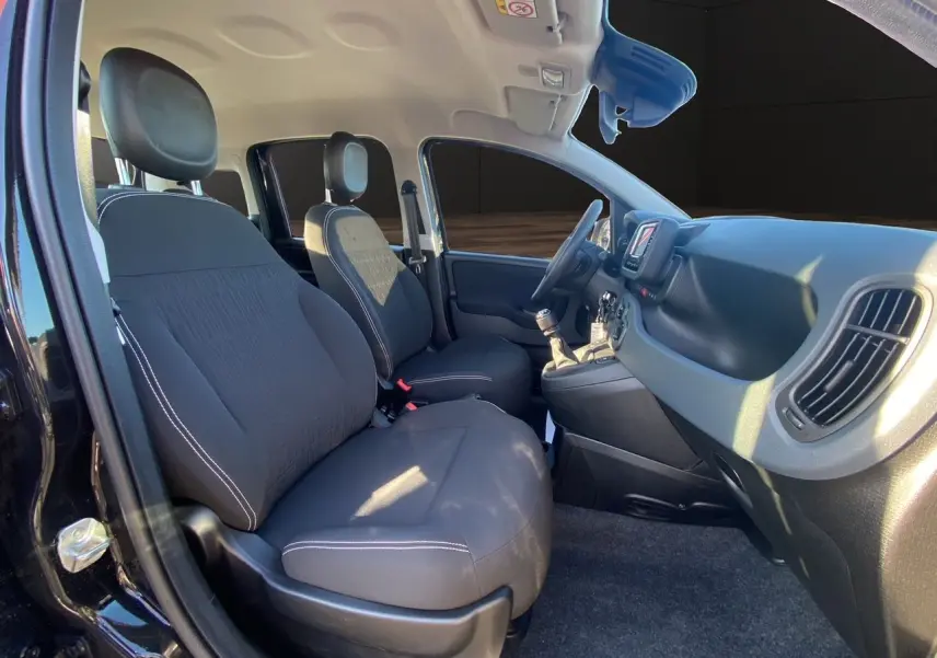 Intérieur avant noir de la Fiat Panda 2025, vue côté gauche montrant sièges, volant et tableau de bord avec écran tactile.